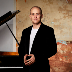 Simon Tedeschi posing by a piano